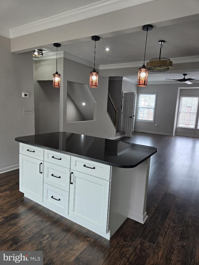 kitchen featuring crown molding, open floor plan, dark wood-style floors, dark countertops, and pendant lighting