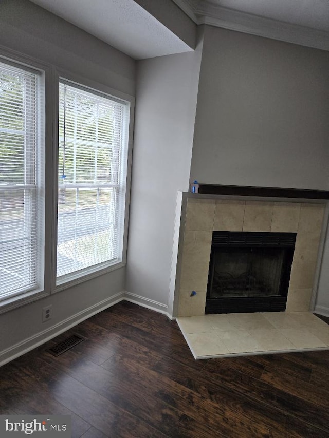 unfurnished living room with a tile fireplace, wood finished floors, visible vents, and baseboards