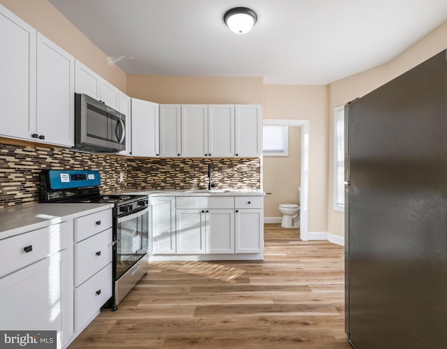 kitchen featuring a sink, tasteful backsplash, light wood-type flooring, and stainless steel appliances