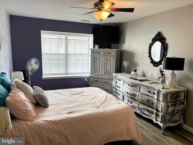 bedroom with baseboards, wood finished floors, visible vents, and a ceiling fan