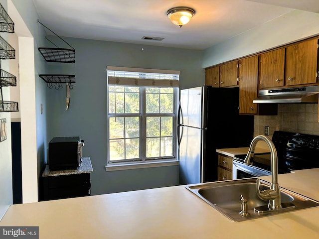 kitchen featuring under cabinet range hood, a healthy amount of sunlight, stainless steel range with electric stovetop, and brown cabinetry