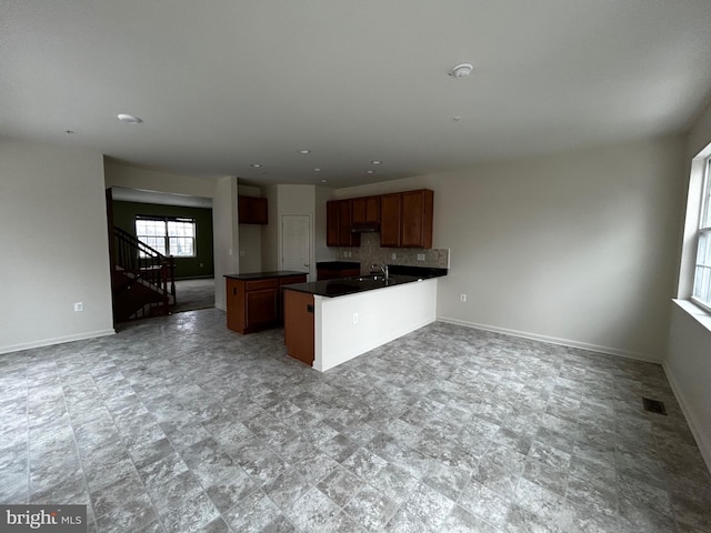 kitchen featuring dark countertops, a peninsula, baseboards, and open floor plan