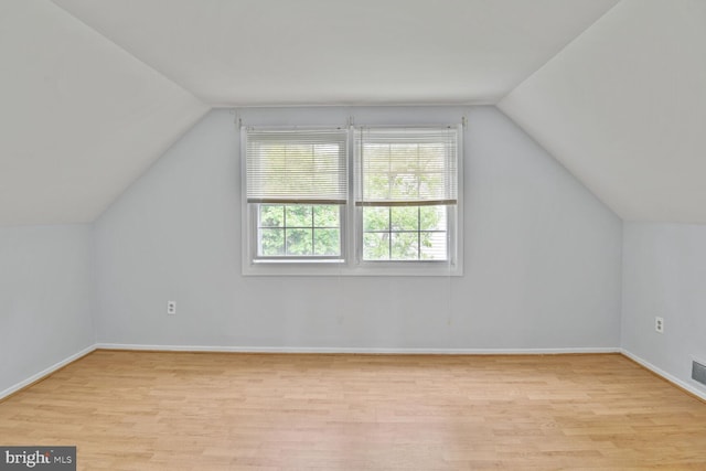 additional living space featuring baseboards, visible vents, lofted ceiling, and light wood-style floors