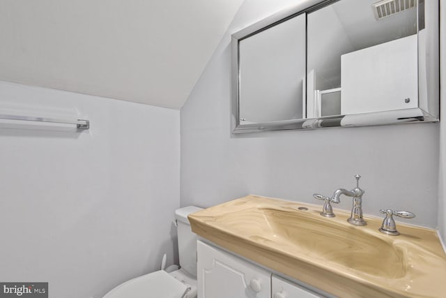 bathroom with vanity, lofted ceiling, toilet, and visible vents