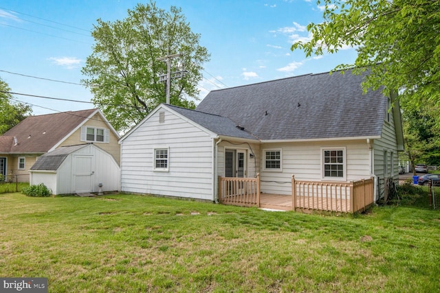 rear view of house featuring roof with shingles, a shed, a yard, and a deck