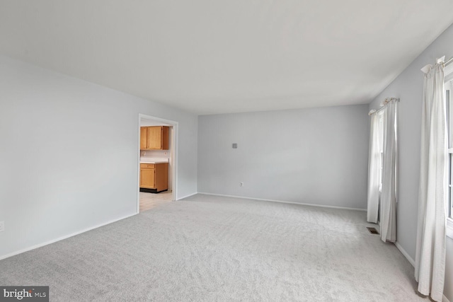empty room featuring baseboards, light colored carpet, and visible vents