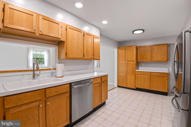 kitchen featuring brown cabinetry, a sink, light countertops, stainless steel appliances, and recessed lighting