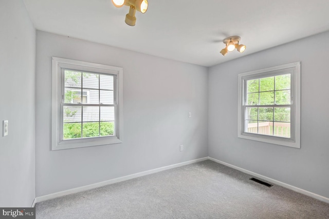 carpeted empty room with plenty of natural light, baseboards, and visible vents