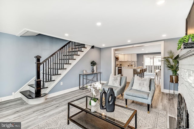 living room with light wood-type flooring, baseboards, stairway, and recessed lighting