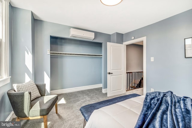 bedroom featuring a closet, baseboards, carpet flooring, and a wall mounted AC