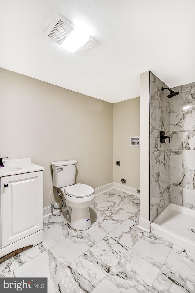 bathroom with tiled shower, a sink, and baseboards