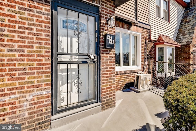 doorway to property with ac unit and brick siding