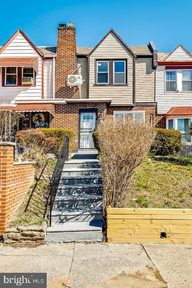 townhome / multi-family property with a chimney and brick siding