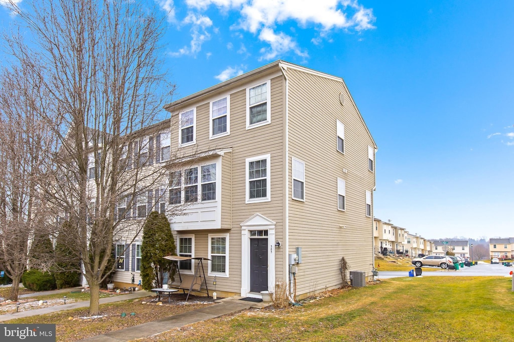 townhome / multi-family property featuring cooling unit and a front yard