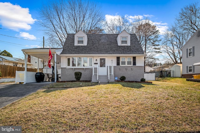 view of front of house with driveway, brick siding, and fence