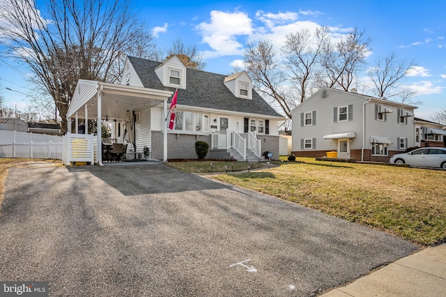 cape cod-style house with brick siding, aphalt driveway, roof with shingles, fence, and a front yard