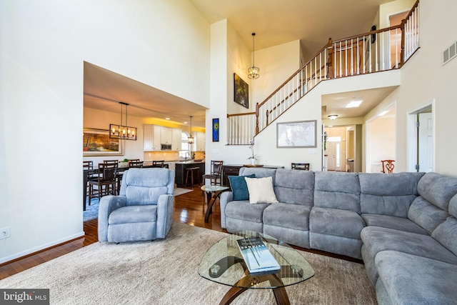 living room featuring visible vents, baseboards, dark wood finished floors, and a chandelier