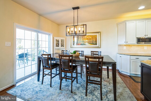 dining area with recessed lighting, baseboards, dark wood-type flooring, and an inviting chandelier