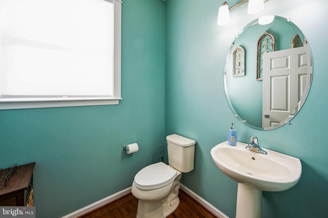 bathroom featuring toilet, wood finished floors, baseboards, and a sink