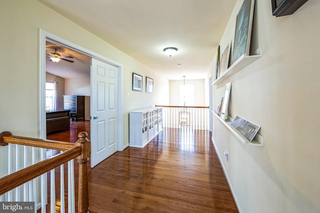 hallway with baseboards, an upstairs landing, and wood finished floors