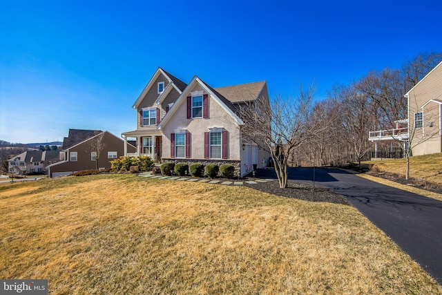 traditional home with a front lawn, driveway, and stucco siding