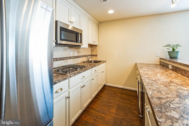 kitchen with backsplash, dark wood-style floors, white cabinets, stainless steel appliances, and a sink