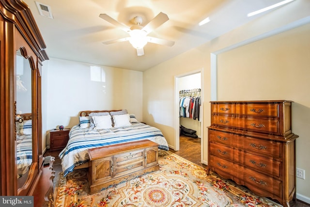 bedroom with visible vents, a walk in closet, a closet, baseboards, and ceiling fan