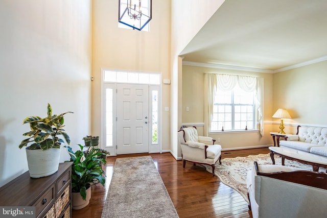 entrance foyer featuring baseboards, a high ceiling, wood finished floors, and ornamental molding