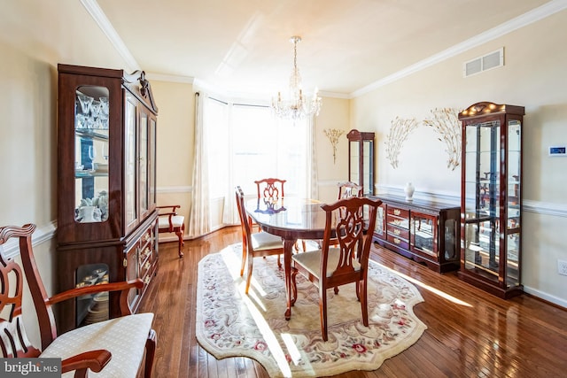 dining room with crown molding, a notable chandelier, visible vents, and wood-type flooring