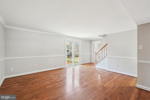 spare room featuring stairway, baseboards, hardwood / wood-style floors, and ornamental molding