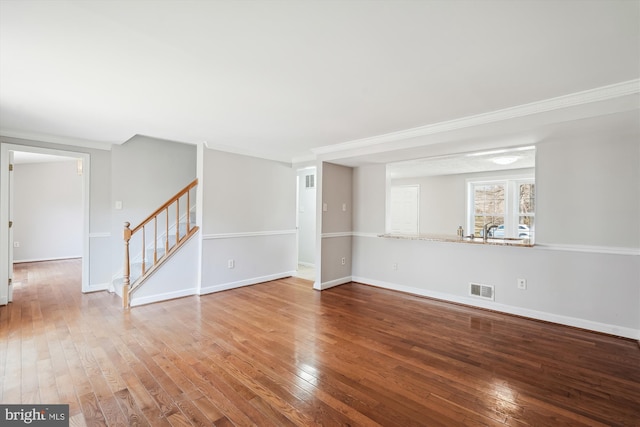 spare room featuring hardwood / wood-style flooring, stairway, baseboards, and visible vents