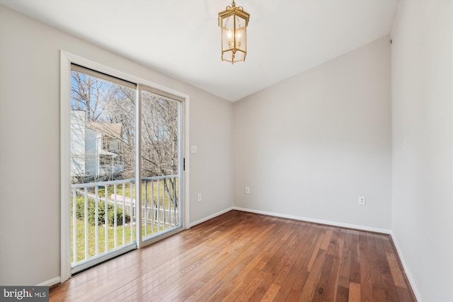 unfurnished room with baseboards, an inviting chandelier, and hardwood / wood-style flooring