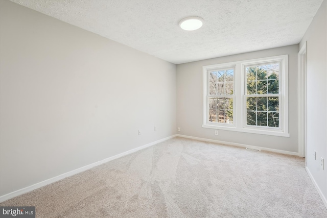 unfurnished room featuring light colored carpet, baseboards, and a textured ceiling