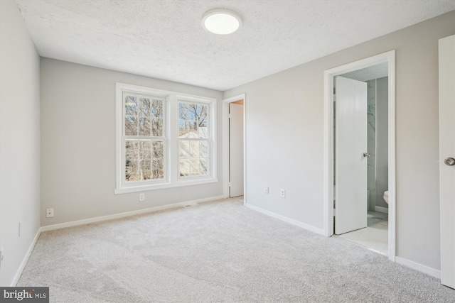 unfurnished bedroom featuring carpet flooring, connected bathroom, a textured ceiling, and baseboards