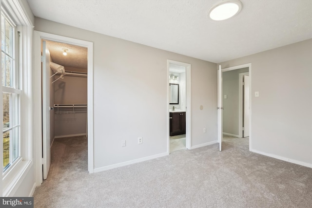 unfurnished bedroom with carpet flooring, baseboards, a textured ceiling, and a spacious closet