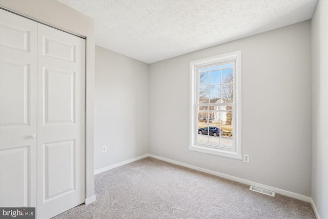 unfurnished bedroom with a closet, visible vents, baseboards, and carpet floors