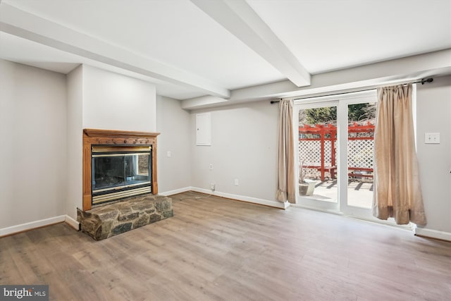 unfurnished living room featuring beam ceiling, a fireplace, baseboards, and wood finished floors