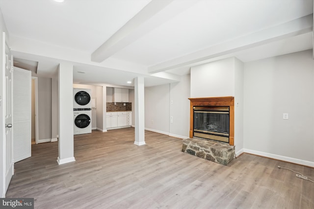 finished below grade area featuring baseboards, light wood-type flooring, recessed lighting, stacked washer and clothes dryer, and a fireplace