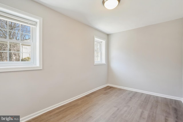 spare room with baseboards and light wood-style floors