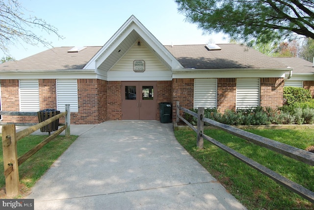 view of front facade featuring fence, brick siding, and a shingled roof