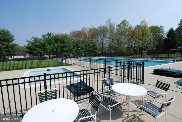 pool with a patio area and fence