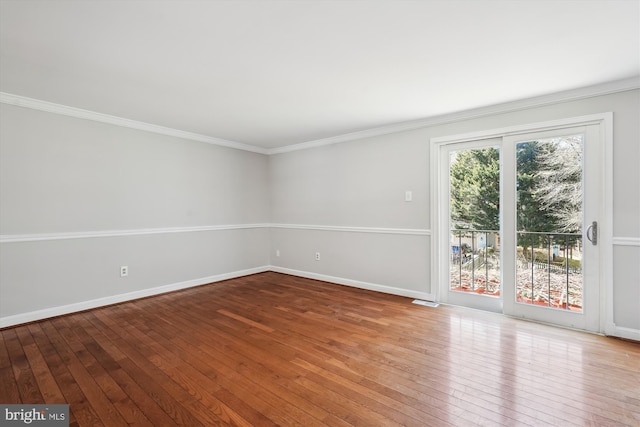 empty room featuring hardwood / wood-style flooring, visible vents, baseboards, and ornamental molding