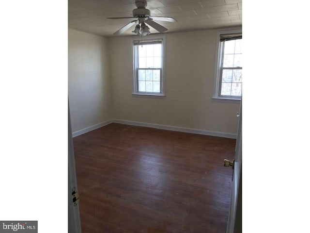 spare room with dark wood-style floors, ceiling fan, and baseboards