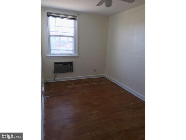 empty room featuring ceiling fan, baseboards, dark wood-style flooring, and a wall mounted AC