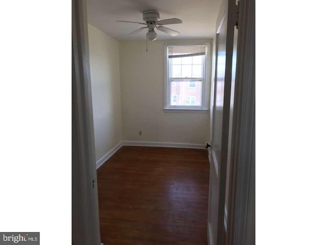 empty room featuring dark wood finished floors, baseboards, and ceiling fan