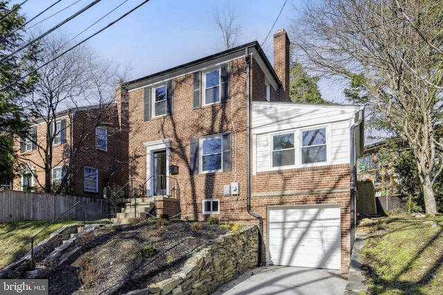 view of front facade featuring driveway, brick siding, a chimney, and fence