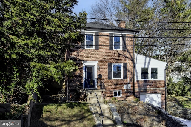 colonial inspired home featuring a garage, brick siding, and a chimney