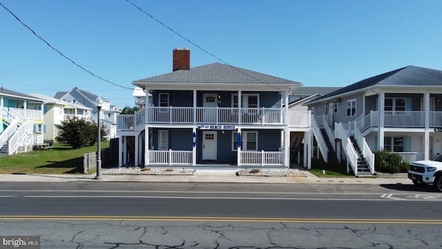 view of front of home featuring stairs, a porch, a residential view, and a chimney