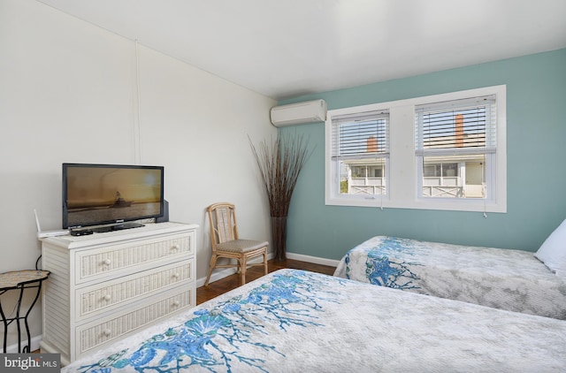 bedroom featuring baseboards, an AC wall unit, and wood finished floors