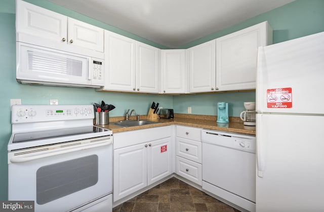 kitchen featuring white cabinetry, white appliances, stone finish flooring, and a sink